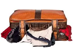 A suitcase crammed past closing, clothes spilling out of every side.